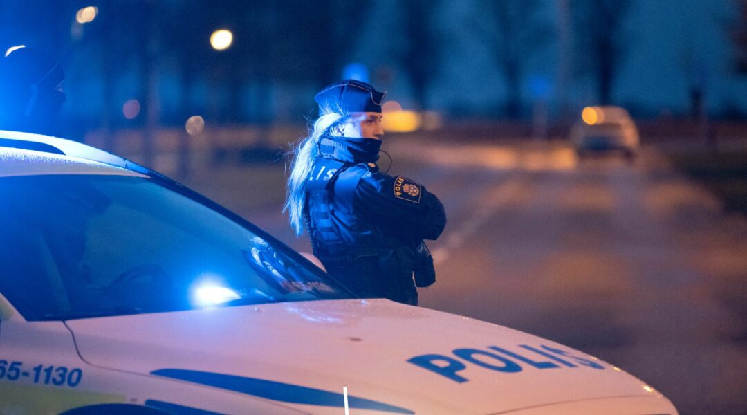 Polis står vid polisbil